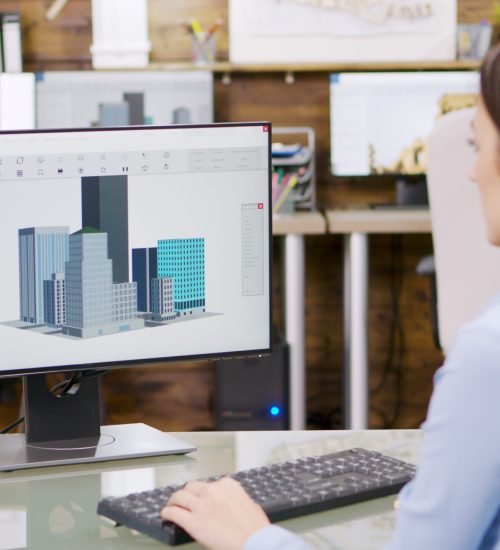 Female architect making 3d building models on computer Female architect making 3d building models on computer. Architect holding blueprint.
